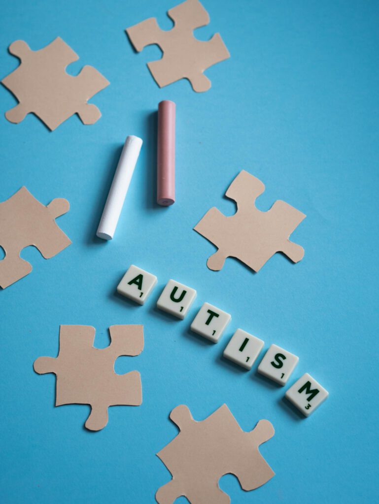 Puzzle pieces, chalk, and autism text symbolize awareness on blue background.